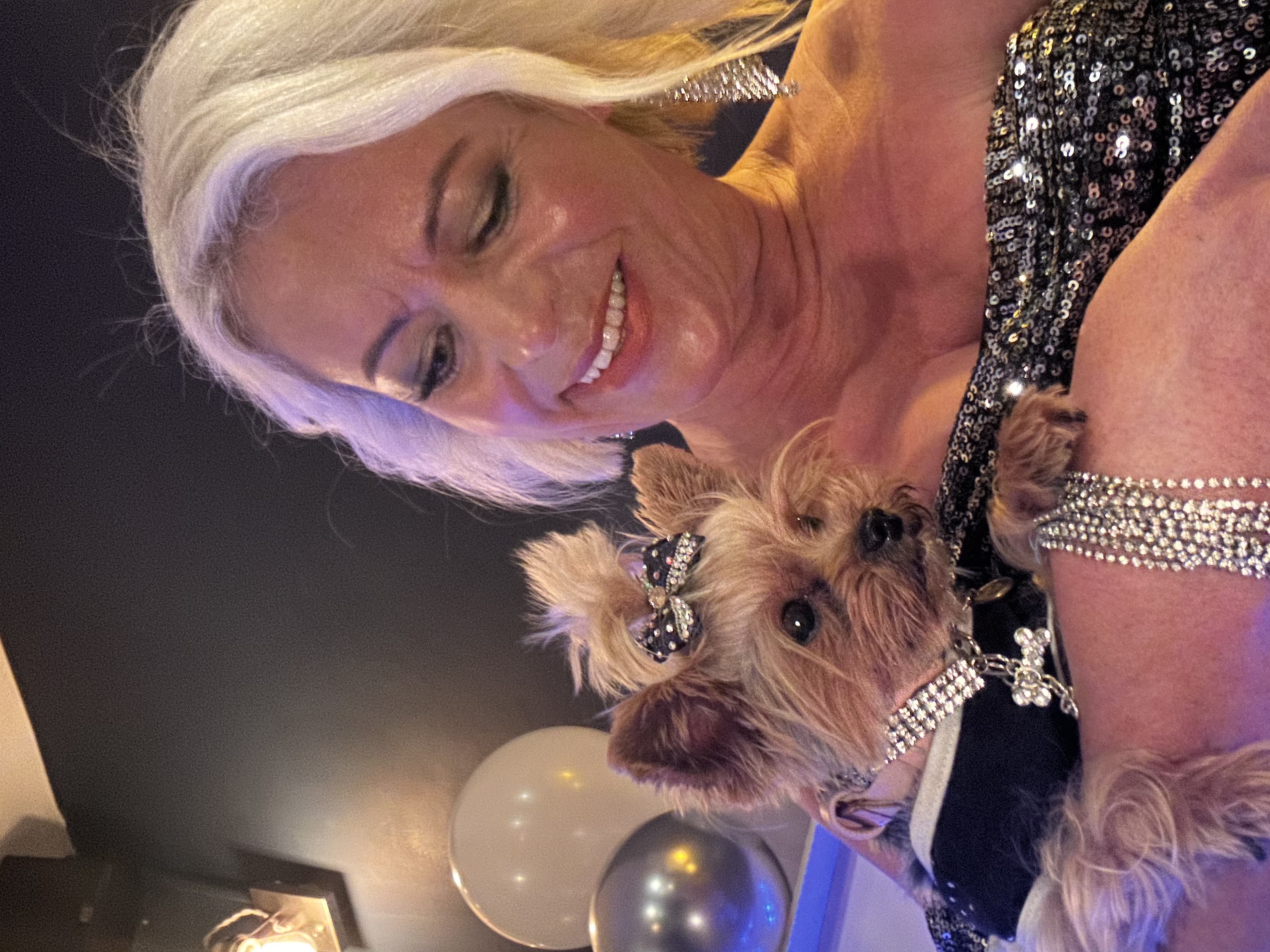 Esme in a rhinestone collar held by a guest in a sequined dress at an event